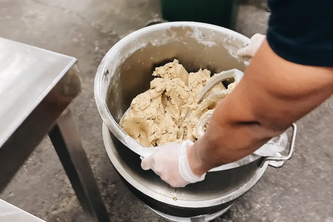 Chef stirring chunky cookie dough in a stainless steel bowl — Molly Woppy artisan baking process featured on ‘From Our Ovens to the Headlines’